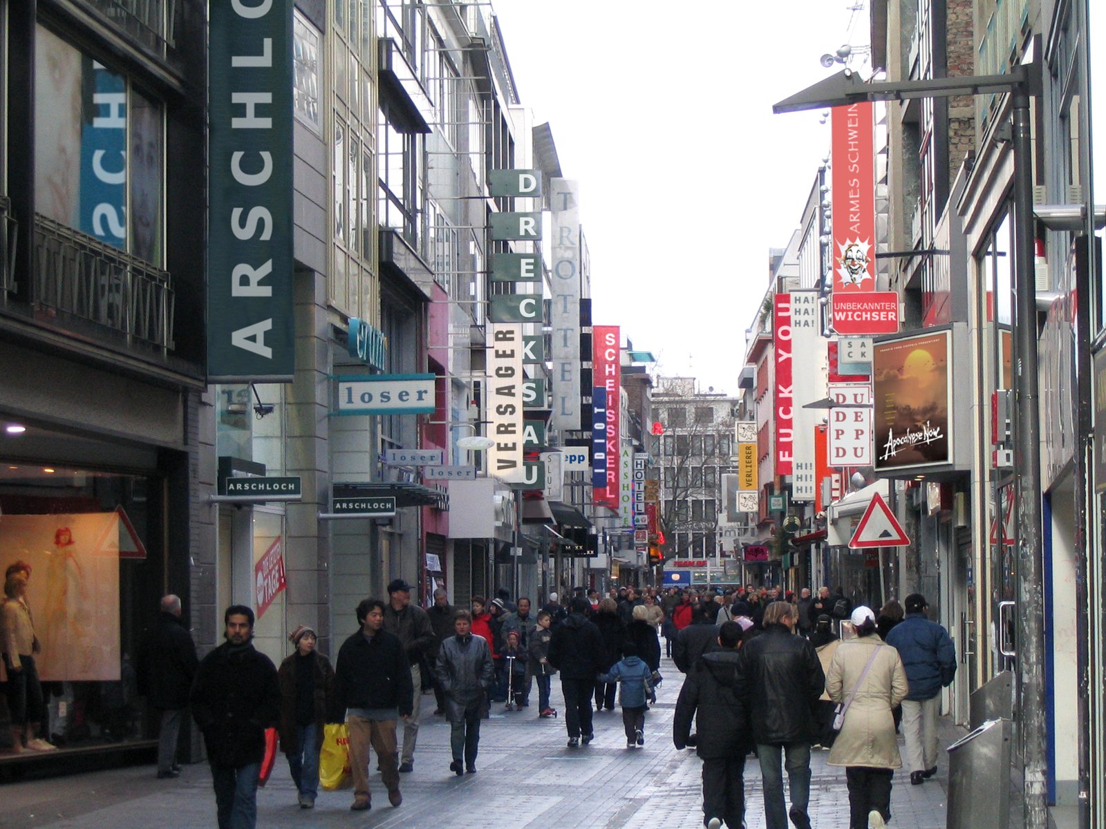 A busy shopping street in Cologne, the shop signs digitally altered to read ARSCHLOCH and ASSHOLE