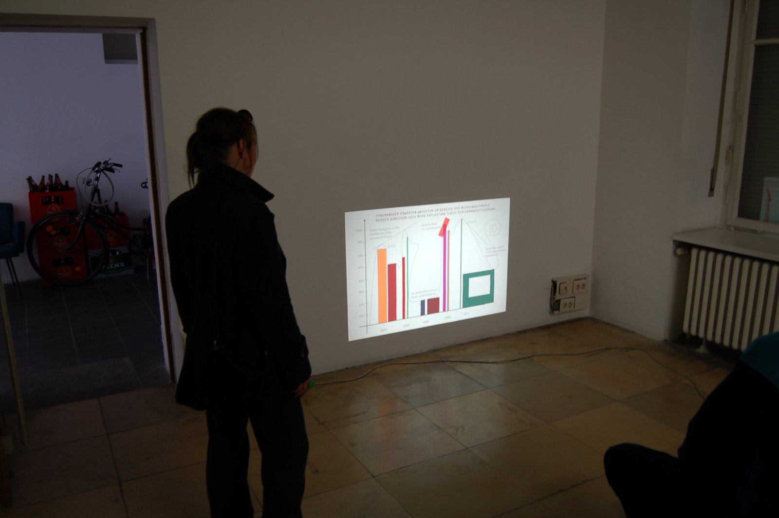 A visitor looking at a small bar-chart projection on the gallery wall