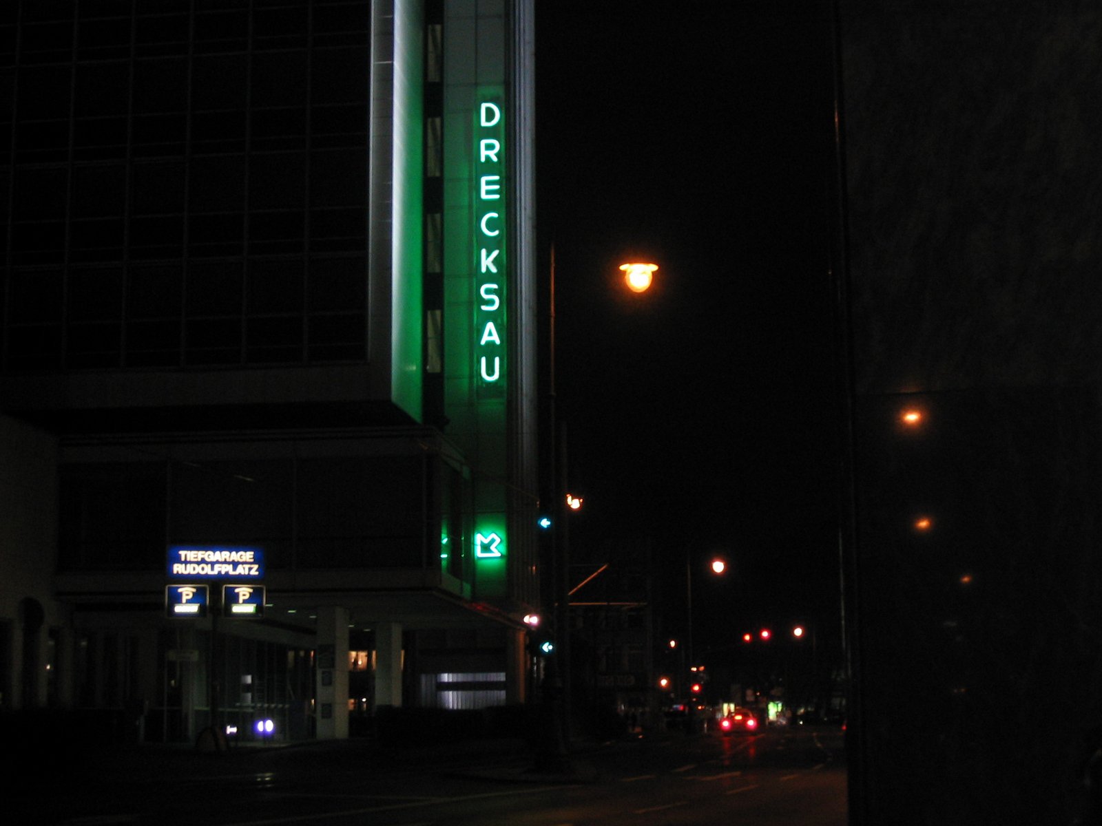 A building in Cologne at night with green neon reading DRECKSAU