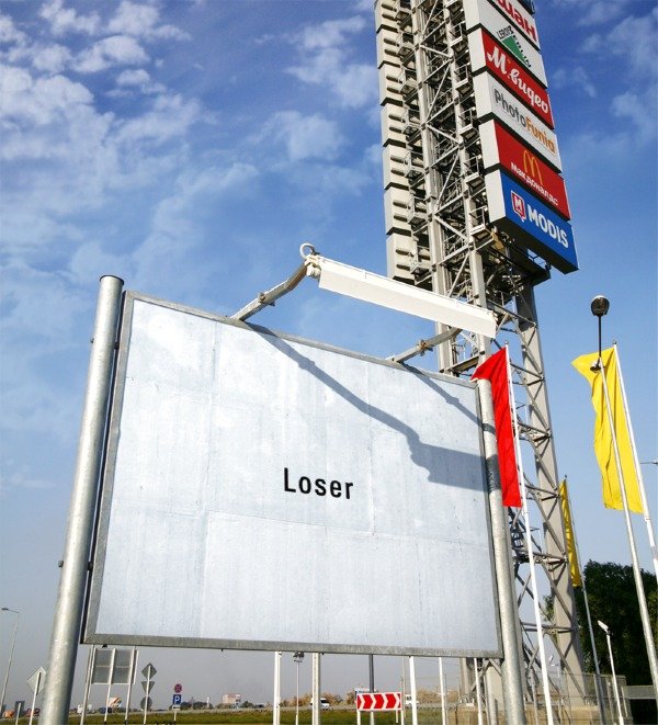 An empty billboard against the sky carrying a single word: Loser